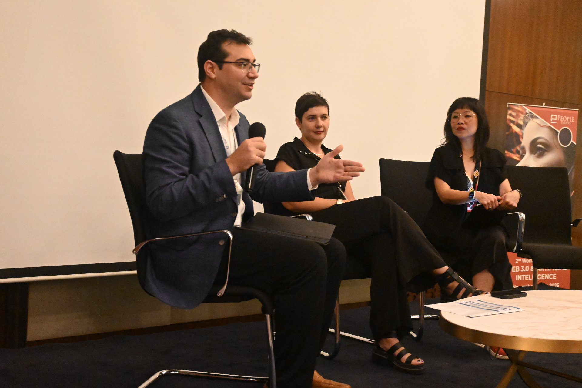 Panelists speaking on stage during a blockchain event